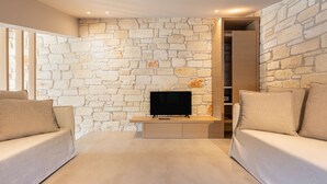 Una sala de estar moderna con una pared de piedra, un televisor de pantalla plana y dos sofás.