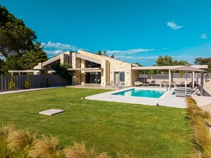 A modern house with a swimming pool, outdoor seating, and a covered patio area.