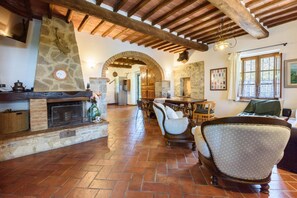 A rustic interior with a stone fireplace, wooden furniture, and an arched doorway leading to another room.