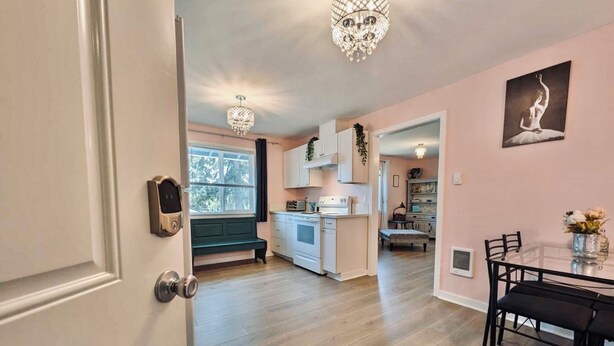 A spacious kitchen with white cabinets, a dining area with a glass table, and a chandelier. - Audrey- an ode to an icon (Salem)