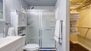 Un baño pequeño con inodoro, cabina de ducha y toallero.