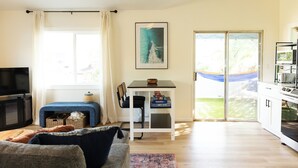 Un salon avec un canapé, un téléviseur, une petite table sur laquelle se trouve un bol, et une bibliothèque.