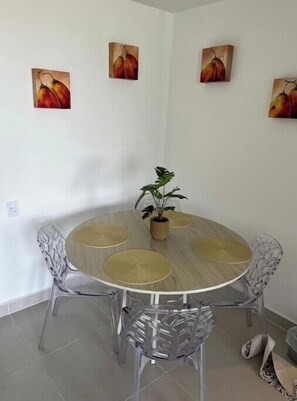Enjoy meals in this dining area with a round table and six chairs, surrounded by artwork and a central potted plant.
