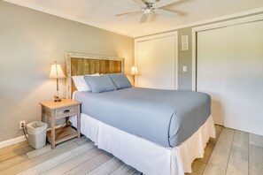 A neatly made bed with a wooden headboard, two bedside lamps, and a small nightstand with a trash bin. - Howe Retreat w/ Fire Pit + Private Boat Dock! (Howe)