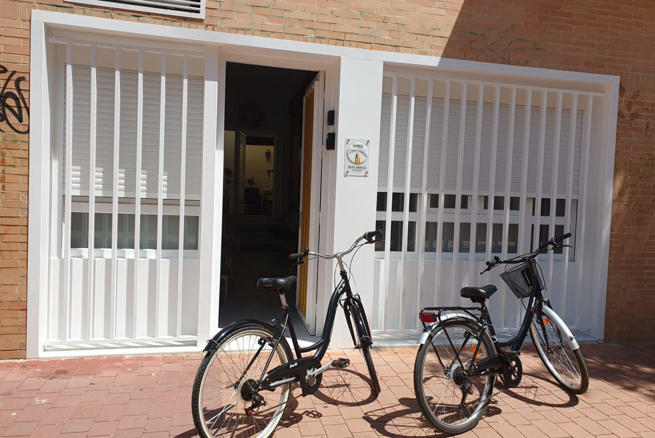 Two bicycles parked in front of a building with white shutters and a sign that reads "AIRBO".