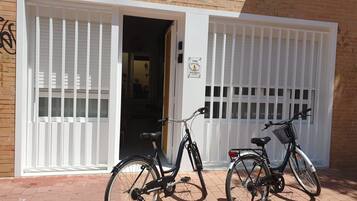Two bicycles parked in front of a building with white shutters and a sign that reads "AIRBO".
