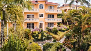 A multi-story building with balconies, surrounded by lush tropical gardens and palm trees. - Paradise On Earth  (Boca Chica)