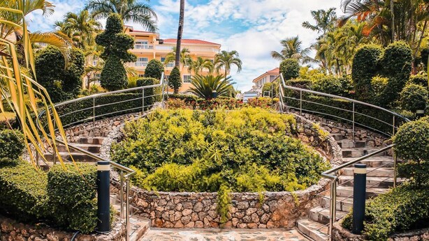 A landscaped area with a stone pathway leading to a circular garden with a metal railing. - Paradise On Earth  (Boca Chica)