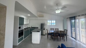 A modern kitchen with a dining area, a ceiling fan, and a view of the outdoors. - Paradise On Earth  (Boca Chica)
