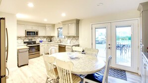 Une cuisine avec des meubles blancs, un four à micro-ondes, une cuisinière et un coin repas comprenant une table et des chaises.