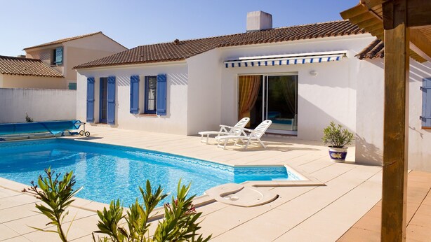 Ein Poolbereich mit klarem, blauem Pool, weißen Wänden und blauen Fensterläden.