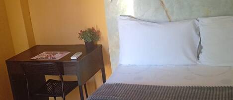 Una habitación de hotel con cama, escritorio y silla.