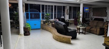 Amplia sala de estar con un mostrador de recepción curvo, un sofá de cuero negro y un sillón reclinable marrón.