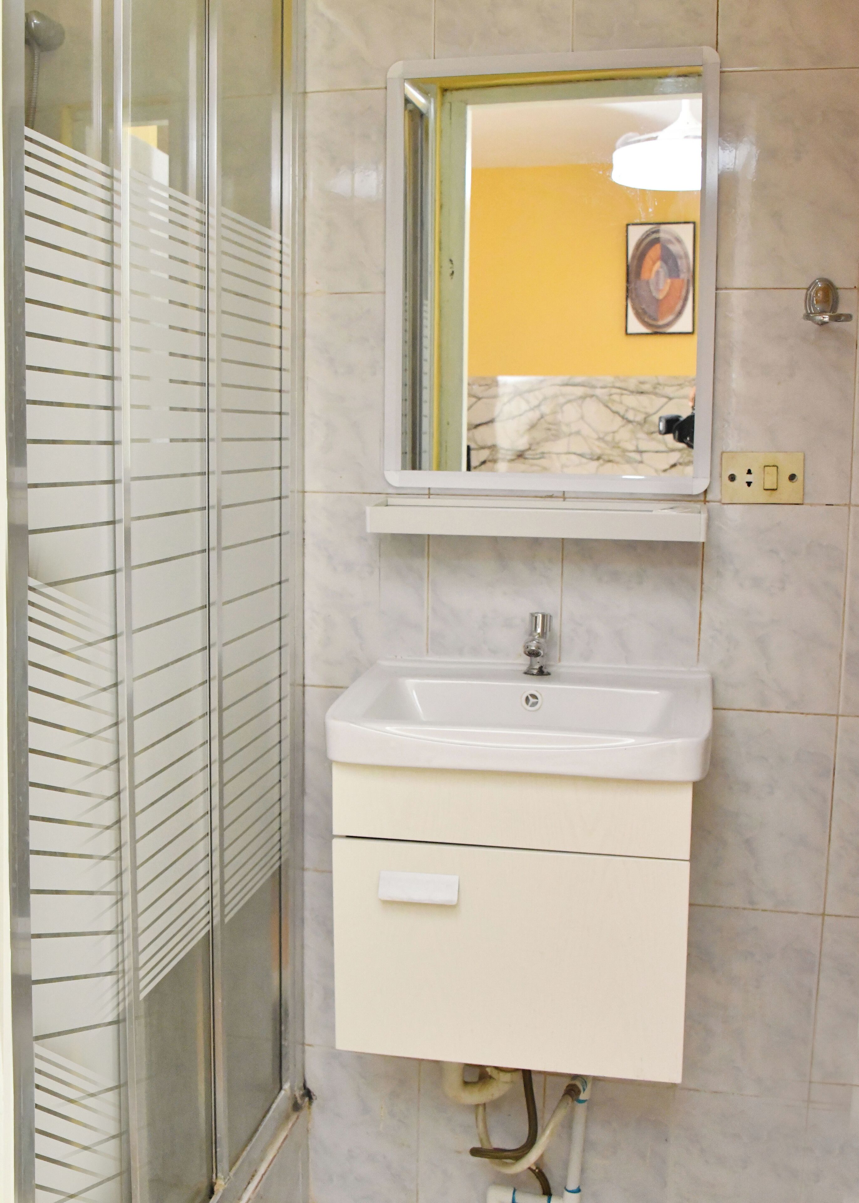 A bathroom with a white sink, a mirror, and a shower with frosted glass doors.