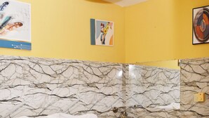 A hotel room with a bed, a marble-patterned wall, a yellow wall, and a ceiling light. - Hotel Condo Mango (Boca Chica)