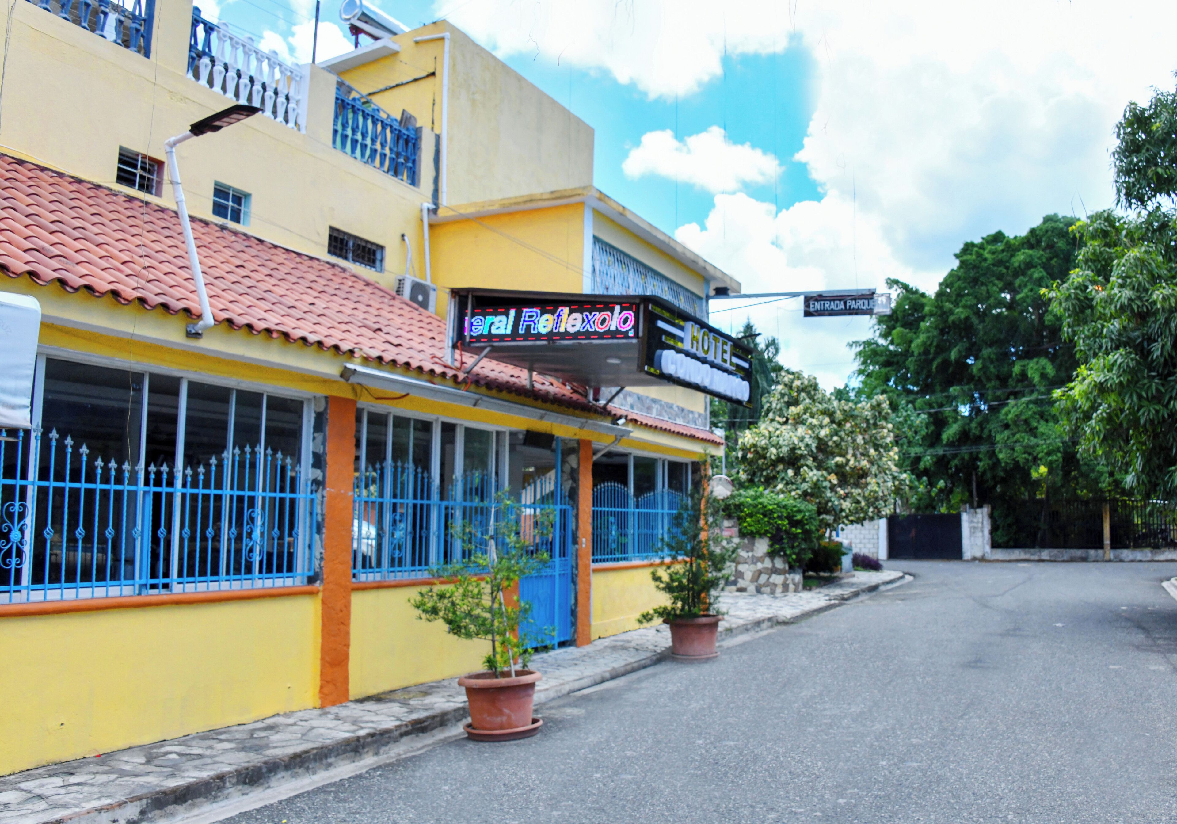 Um hotel com fachada amarela, janelas azuis e uma placa com a inscrição "Hotel Reflexolo".