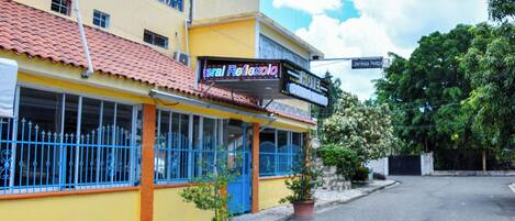 A hotel with a yellow facade, blue windows, and a sign reading "Hotel Reflexolo."