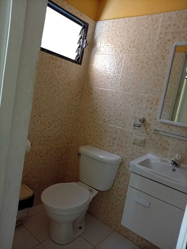 A small bathroom with a toilet, sink, and mirror. - Hotel Condo Mango (Boca Chica)