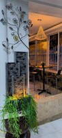Un espacio al aire libre moderno con pared de piedra, detalles de metal decorativo y una lámpara colgante.