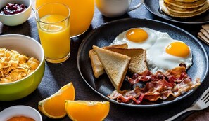 A breakfast plate with eggs, bacon, toast, and orange juice. - Hotel Condo Mango (Boca Chica)