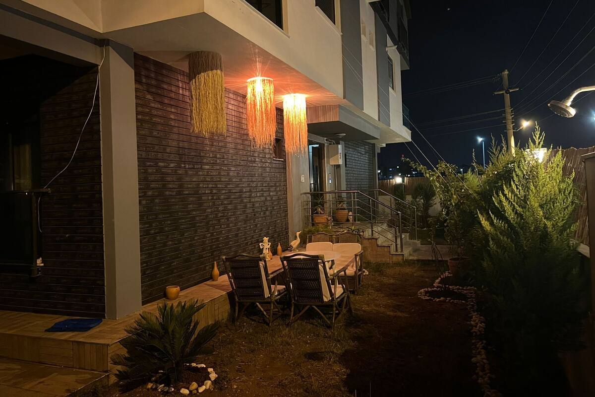A modern outdoor patio with a dining area, a staircase, and potted plants.