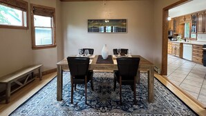 Een eethoek met een tafel, stoelen, een plafondventilator en een vloerkleed.