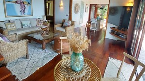 Un amplio salón con muebles de mimbre, una mesa de centro y un jarrón decorativo.