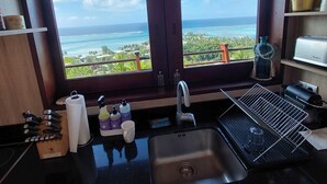 Una cocina con un amplio ventanal que ofrece vista al océano y un balcón.