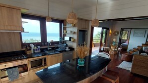 Una cocina moderna con una isla grande, armarios de madera y vistas al océano.