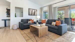 Un salon moderne avec deux canapés gris, une table basse en bois et une grande fenêtre avec des rideaux.
