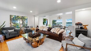 A modern living room with a glass coffee table, leather sofas, and a view of the outdoors. - Puget Sound Waterfront | Eagles, Orcas & Mt. Rainier Views (Gig Harbor)