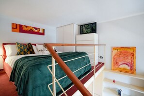Ein Schlafzimmer mit Bett, Fernseher, weißem Kleiderschrank und abstrakter Kunst an den Wänden.
