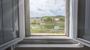 An open window with a view of a river, buildings, and trees.