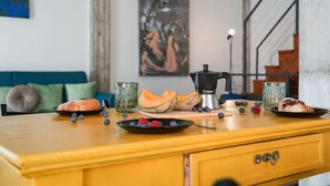 A kitchen counter with a coffee maker, a plate of food, and a bowl of fruit.