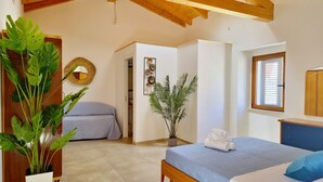 A bedroom with a wooden ceiling, a bed with a blue bedspread, a potted plant, and a mirror on the wall. - [Arcada 5] Deluxe apartment with 2 bathrooms (Orosei)