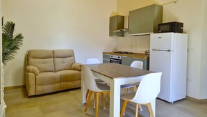 A compact kitchen with a sofa, dining table, and chairs. - [Arcada 5] Deluxe apartment with 2 bathrooms (Orosei)