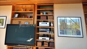 Ein mehrgeschossiges Holzinnere mit Treppe, Einbauschränken und einem Fernseher.