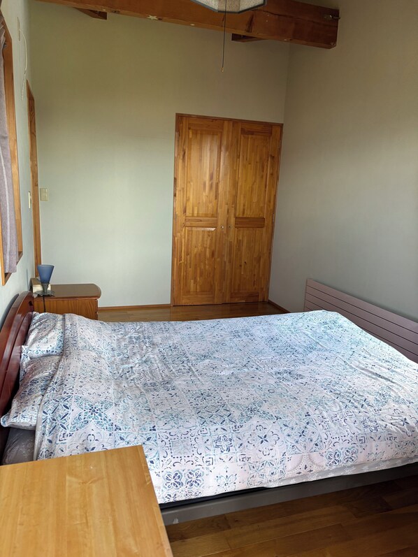 Un dormitorio con una cama de madera, un armario de madera y una mesita de noche con una lámpara.