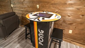 Una mesa de ping pong con marcador digital, un sofá negro y una pared de madera.