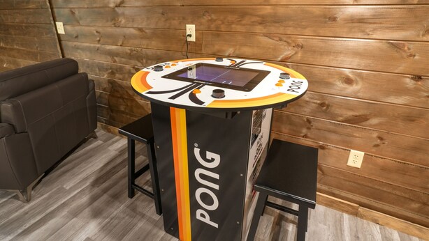 Ein Pingpongtisch mit digitaler Anzeigetafel, ein schwarzes Sofa und eine Holzwand.