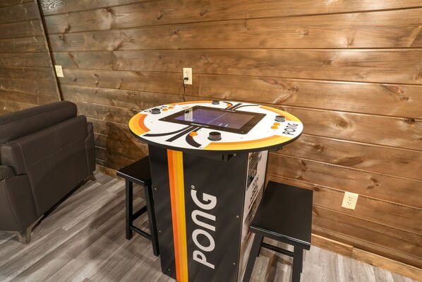 A ping pong table with a digital scoreboard, a black couch, and a wooden wall.
