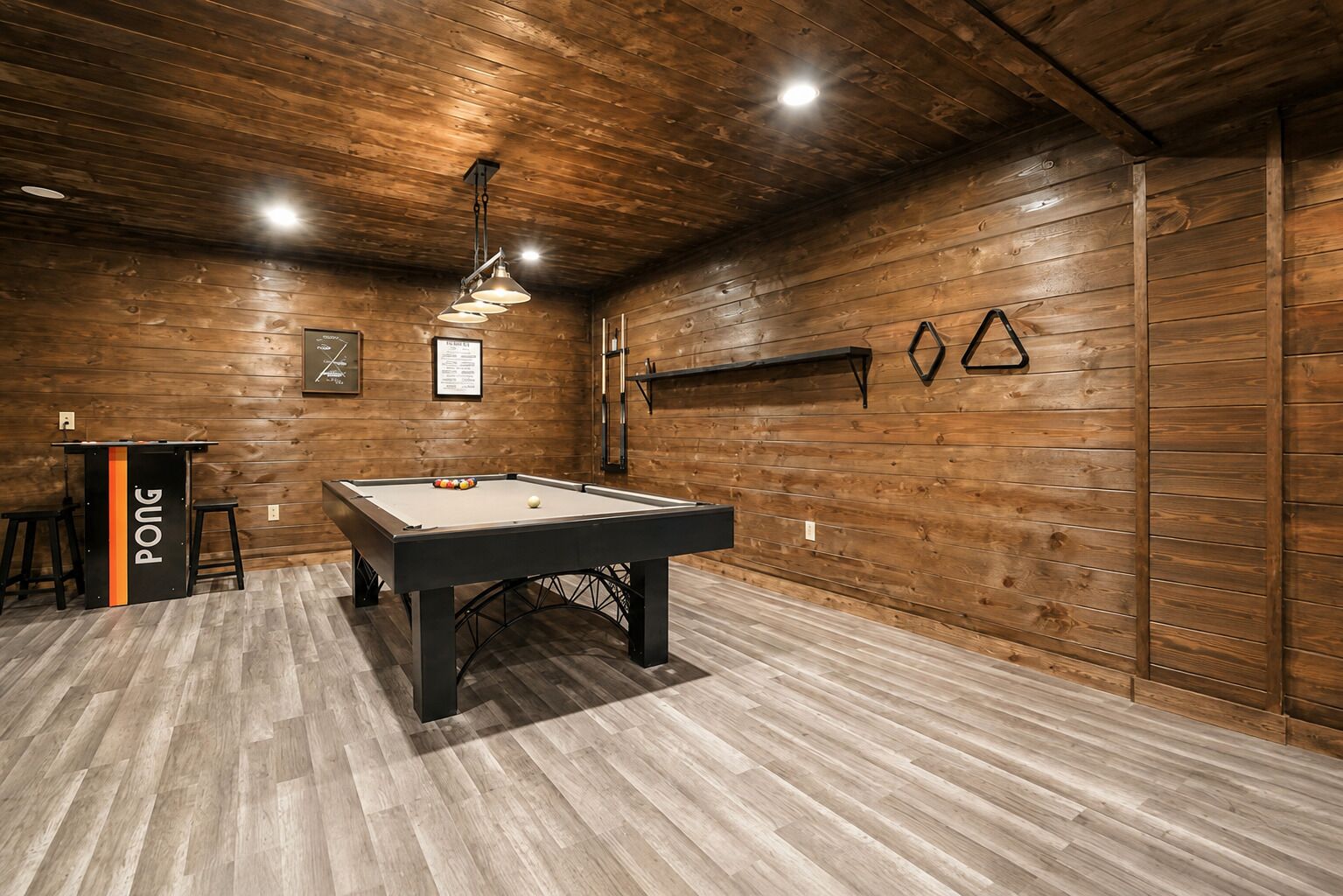 Un tavolo da biliardo in una stanza con pareti e soffitto in legno, un'area bar con sgabelli e un menu incorniciato appeso al muro.