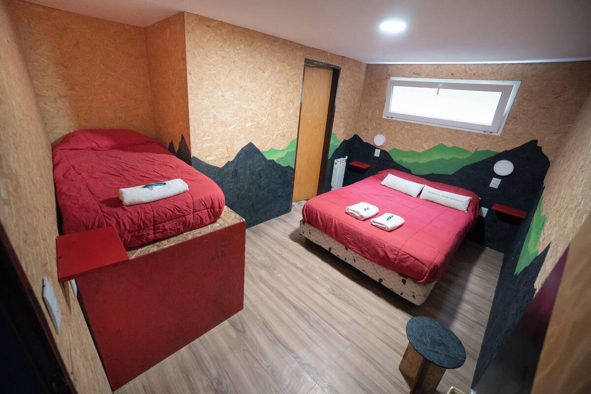 Un dormitorio con dos camas, suelo de madera y decoración con motivos de montaña.
