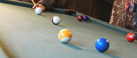 Une table de billard avec une personne qui joue, entourée de différentes billes de couleurs.