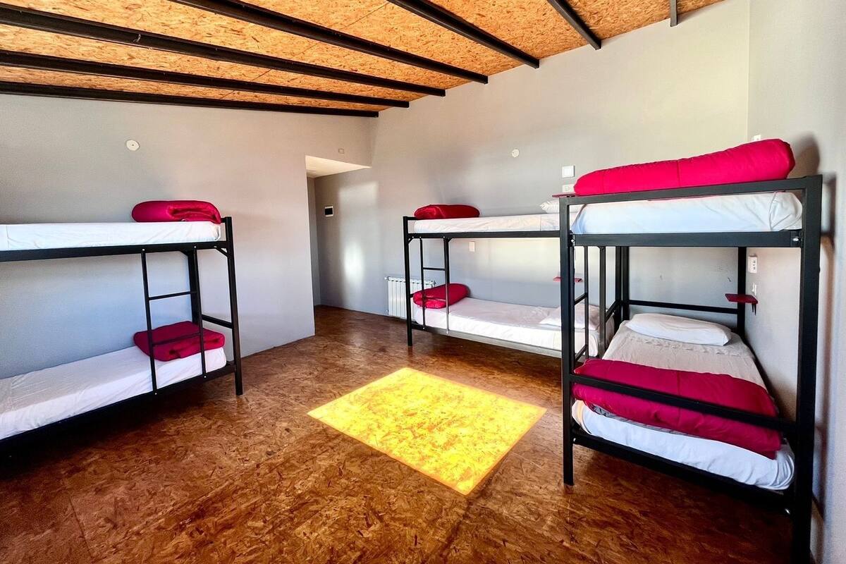 Un dormitorio con literas, suelo de madera y una alfombra amarilla.