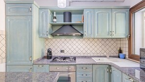 A kitchen with teal cabinets, a gas stove, a sink, and a microwave. - Casa Catalpa near the beach (TORTOLI)