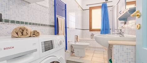 Un baño pequeño con lavadora Bosch, un bidé y una bañera.