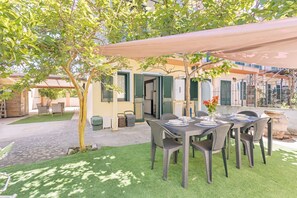An outdoor dining area with a table set for four, surrounded by chairs, under a canopy. - Casa Catalpa near the beach (TORTOLI)