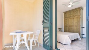 A room with a bed, a table with chairs, a wardrobe, and a ceiling fan. - Casa Catalpa near the beach (TORTOLI)