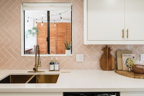 A kitchen with a window, a sink, cabinets, and a countertop.